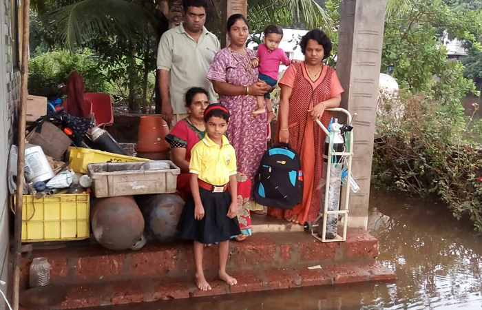 घरांना पाण्याने वेढा दिलेल्या शिरोडकर-फाटक कुटुंबातील सदस्य. (अमित खोत, मालवण)