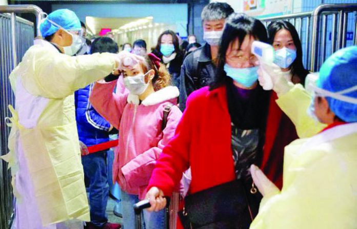 Medical workers take the temperature of passengers after they got off the train in Jiujiang