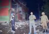Security force officials stand outside a damaged building at a site of a strike near Muzaffarabad in Pakistan-occupied Kashmir
