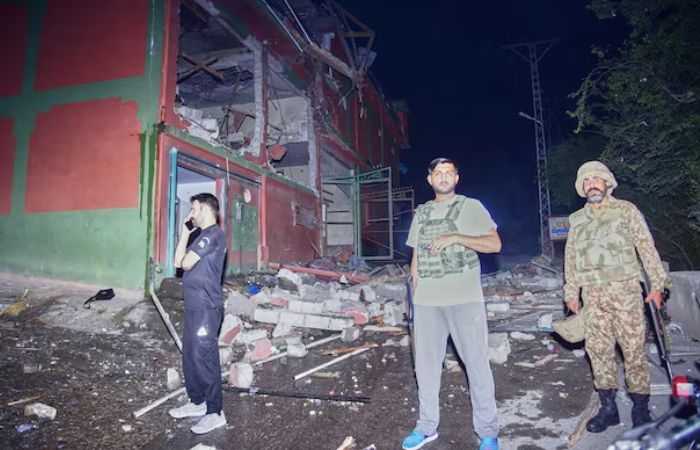 Security force officials stand outside a damaged building at a site of a strike near Muzaffarabad in Pakistan-occupied Kashmir